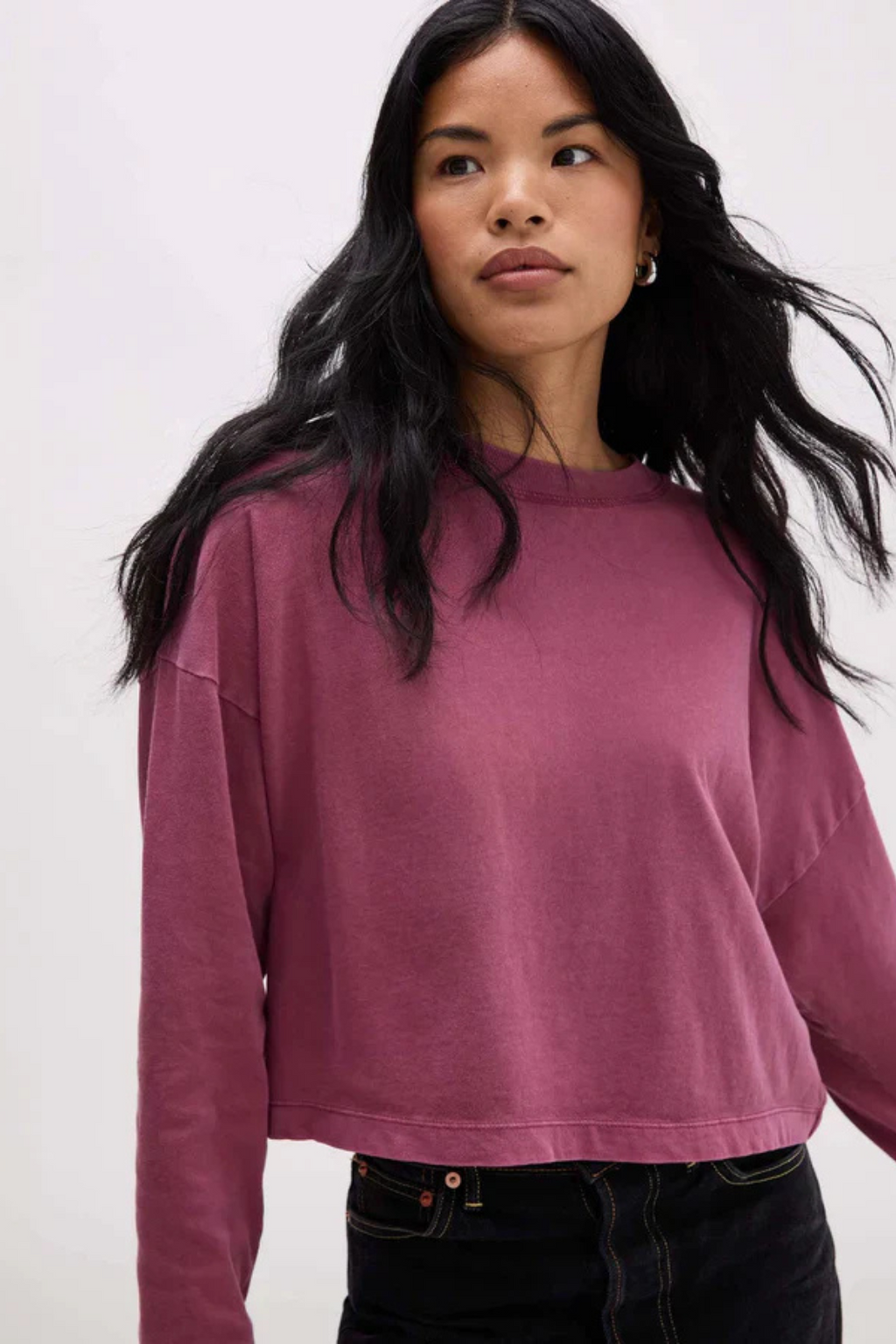 Woman wearing a long sleeve mauve shirt and dark denim. 