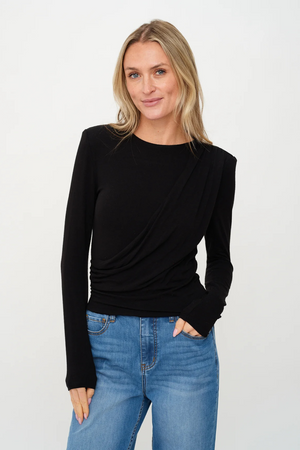 Woman wearing a black long-sleeve top and blue jeans on a white background.
