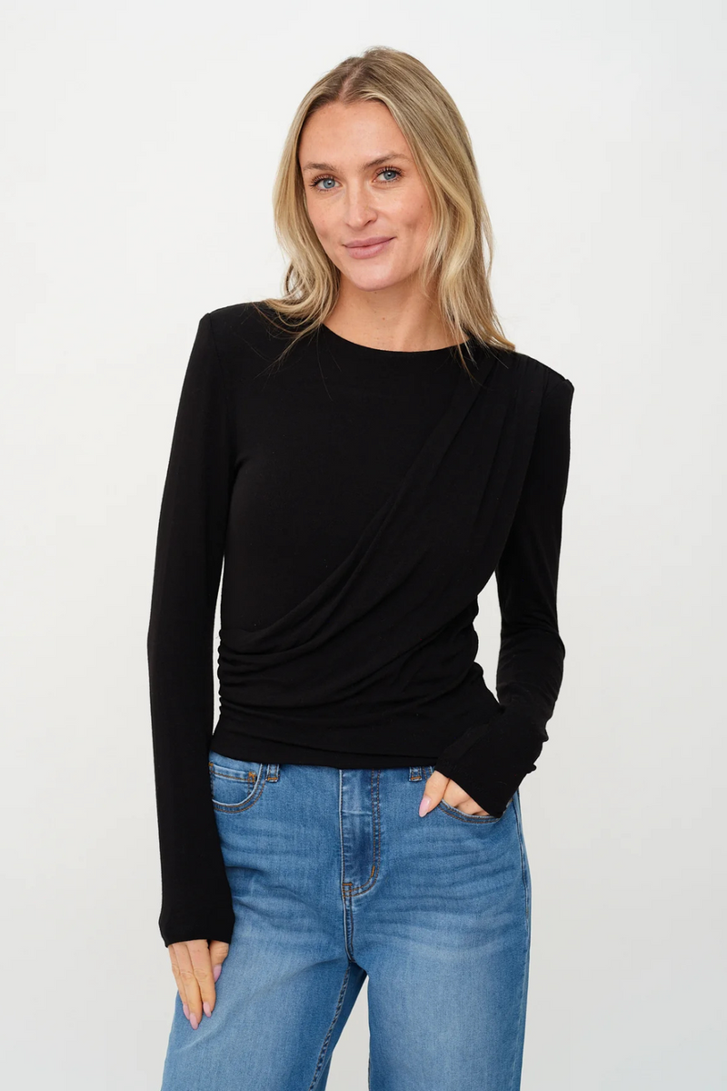 Woman wearing a black long-sleeve top and blue jeans on a white background.