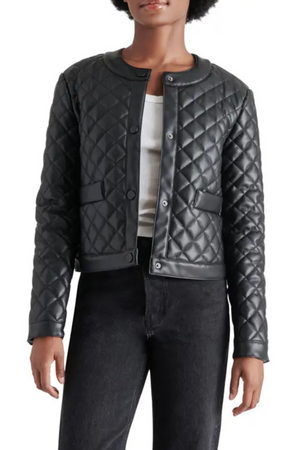 A woman wearing a quilted black jacket with black jeans.