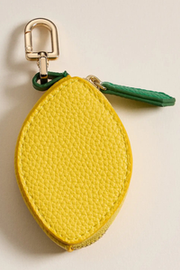 Yellow lemon-shaped keychain with a gold clip on a beige background.