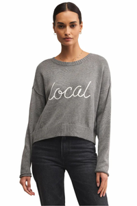 Woman wearing a gray sweater with 'local' text on a white background.