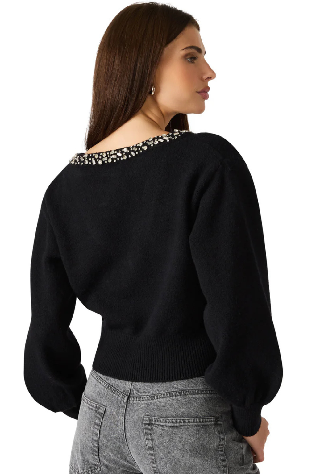 Woman wearing a black sweater with a patterned neckline on a white background.