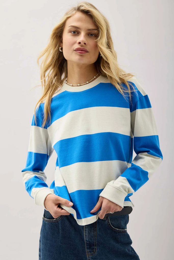 A woman wearing a blue and white striped long sleeve shirt with dark denim. 