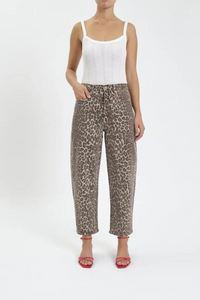 A front view of a woman wearing a white tank top with leopard barrel leg jeans, and red heels. 