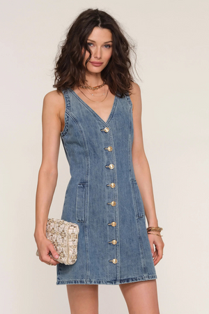 A woman wearing a denim dress holding a purse.