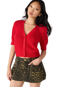 Woman wearing a red cardigan over a leopard print skirt on a white background.