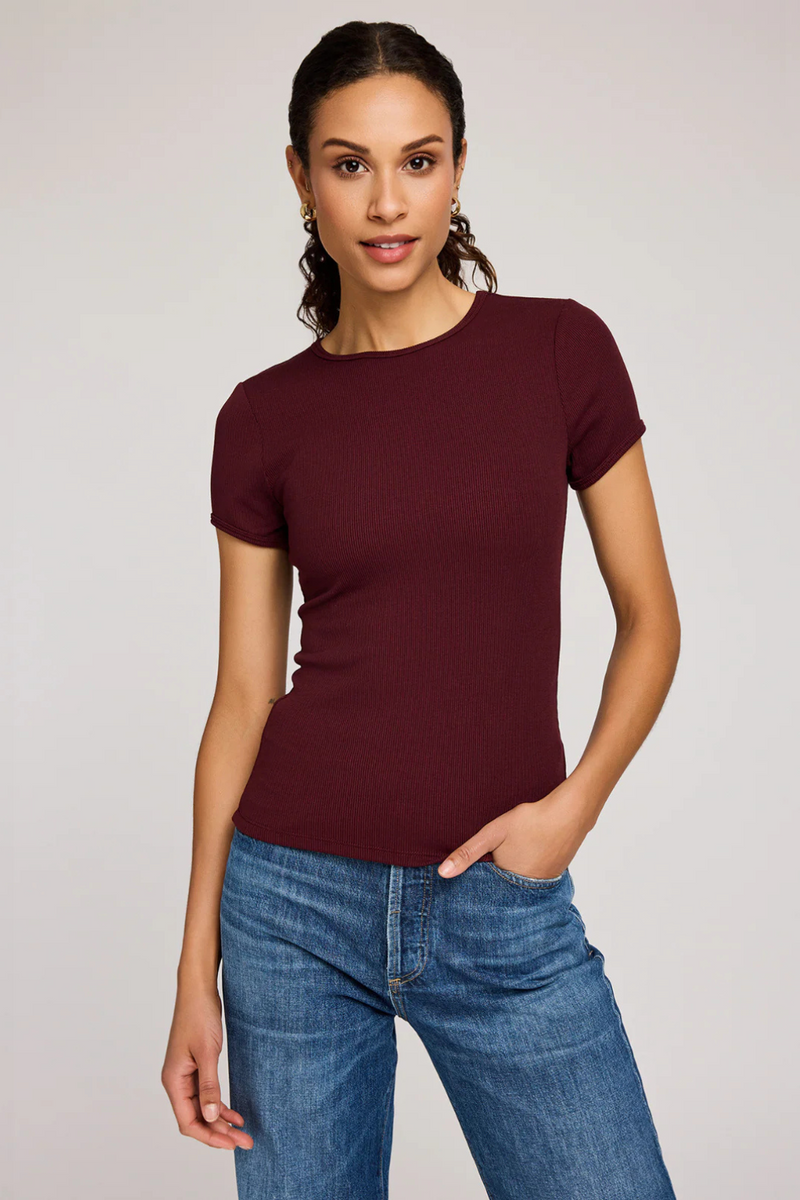 A woman wearing a burgundy t-shirt and jeans.