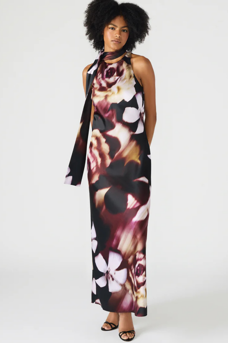 Woman wearing a floral dress with a scarf on a white background.