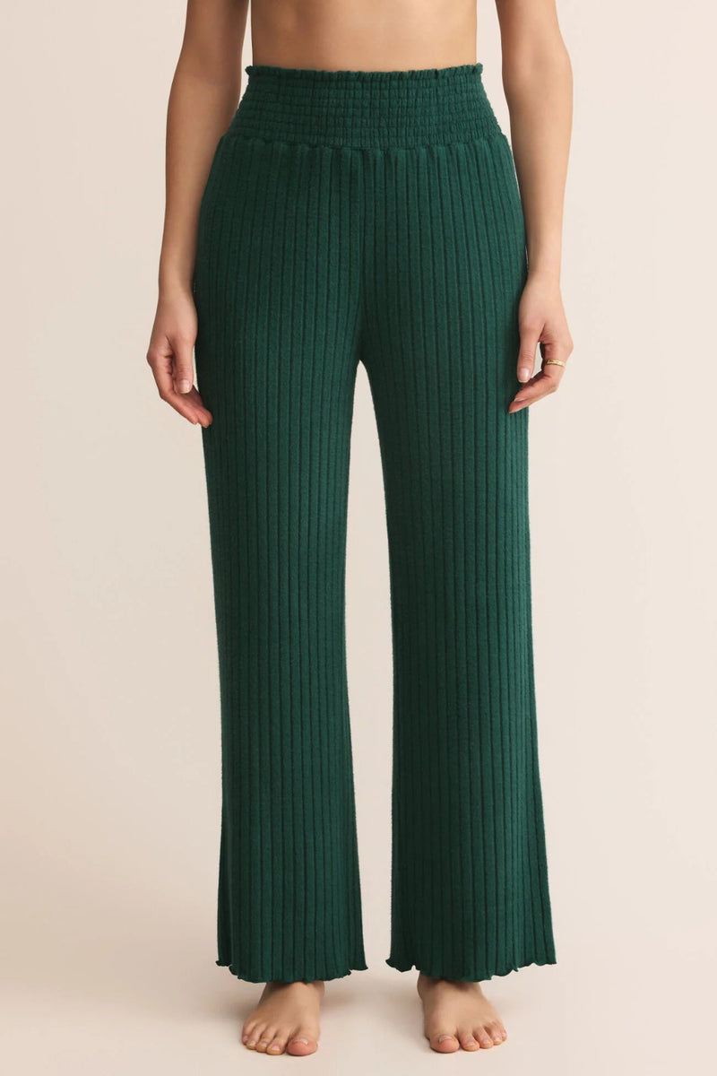Green ribbed pants worn by a person on a beige background.