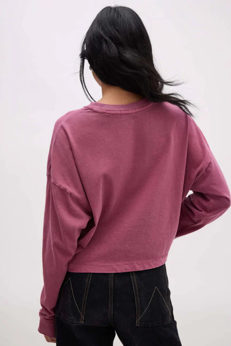 Back view of a woman wearing a long sleeve mauve shirt and dark denim.