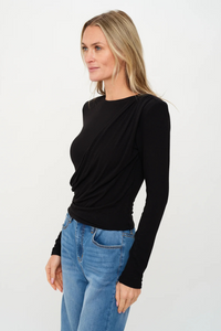 Woman wearing a black long-sleeve top and blue jeans on a white background.