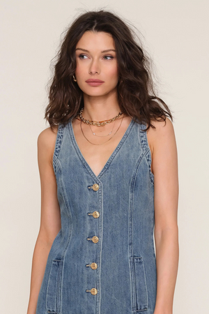 Woman wearing a denim dress with a plain background.