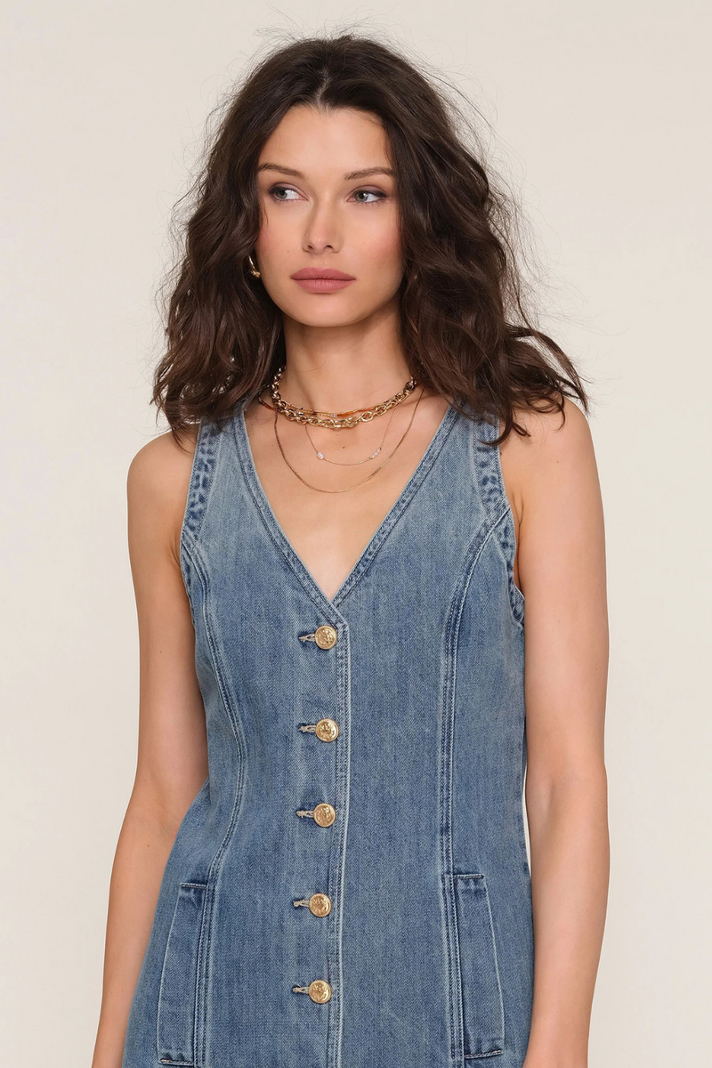 Woman wearing a denim dress with a plain background.