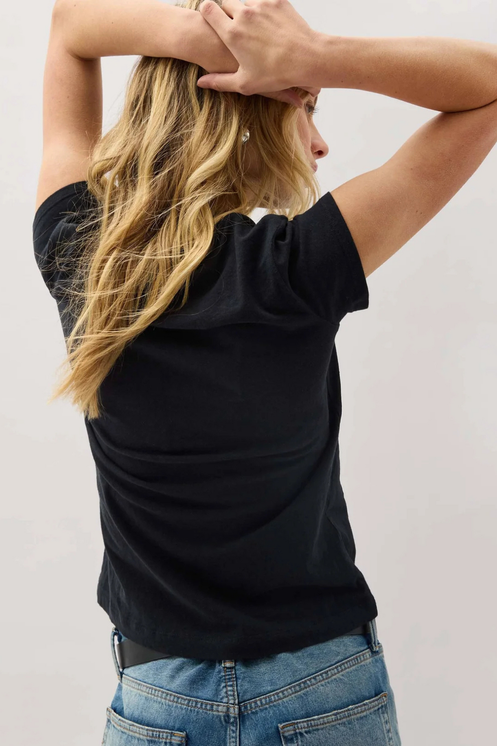 A back view of a woman wearing a black t shirt with blue jeans. 