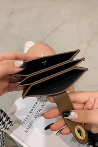 Brown wallet held by a hand with a blurred background.