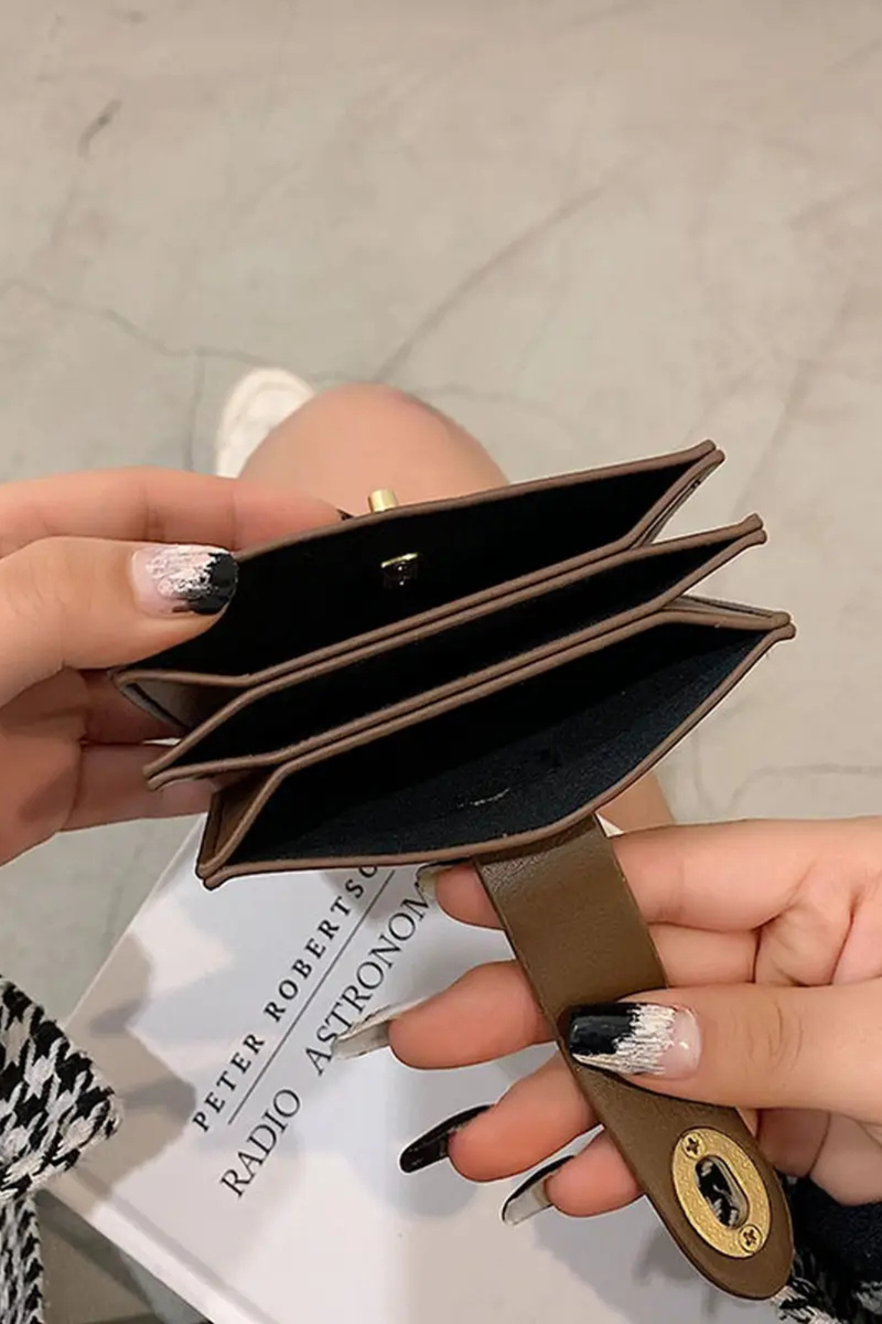 Brown wallet held by a hand with a blurred background.