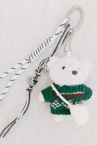 Keychain with a white bear wearing a green sweater on a light background.
