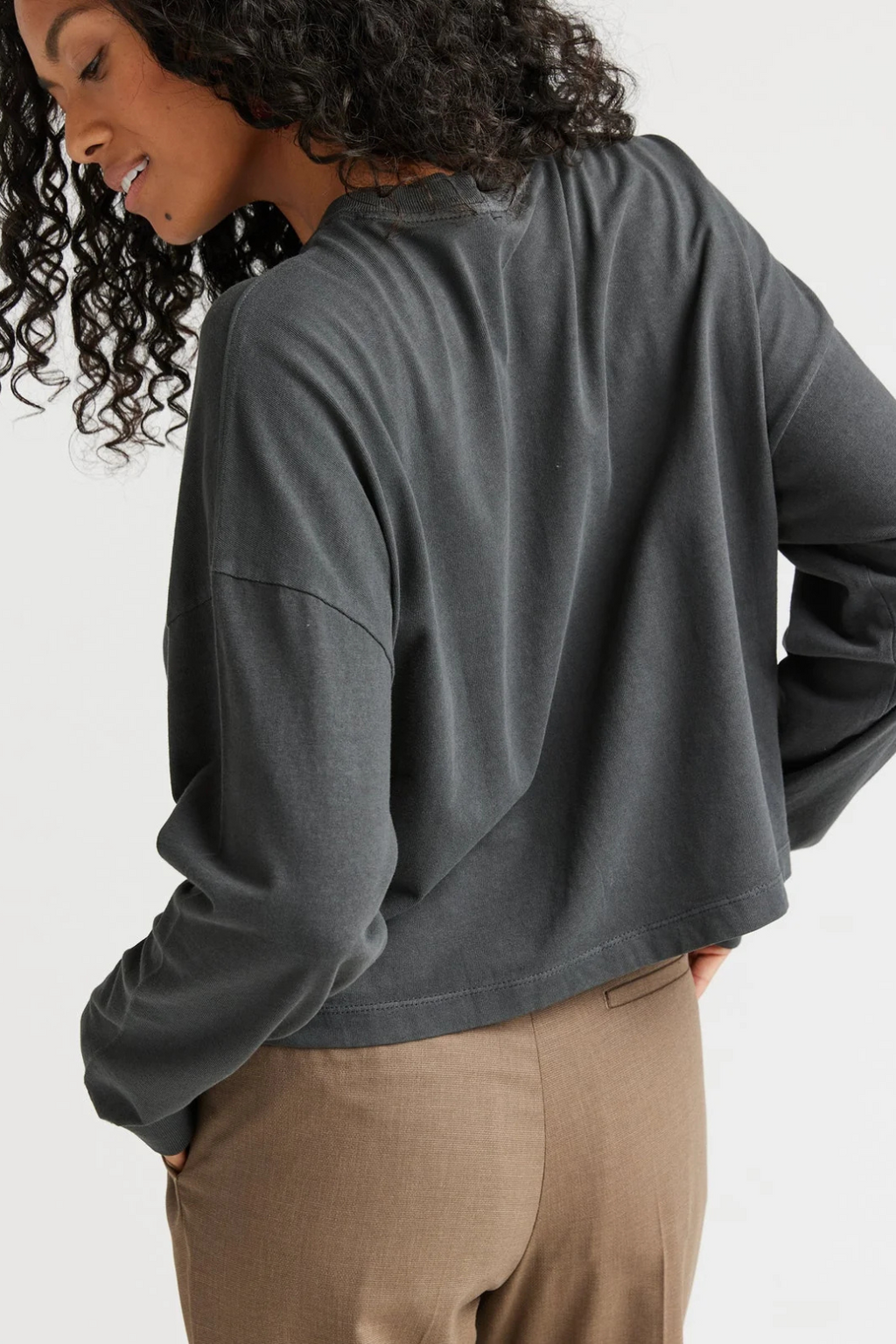 A side view of a woman wearing a long sleeve shirt with tan pants.