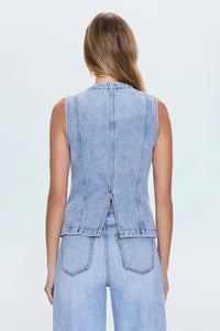 The back view of a woman wearing a denim vest and matching jeans.