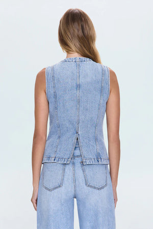 The back view of a woman wearing a denim vest and matching jeans.
