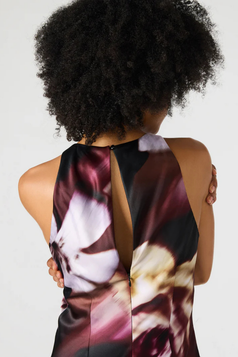Woman wearing a floral dress with a plain background.