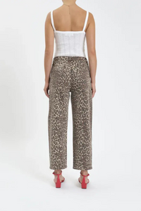 The back view of a woman wearing a white tank top, leopard barrel jeans and red heels. 