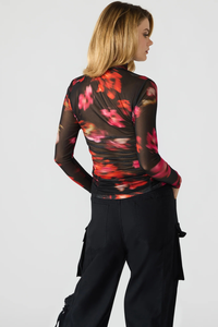 Woman wearing a floral long-sleeve top and black pants on a white background.