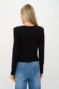 Person wearing a black long-sleeve top and blue jeans on a white background.