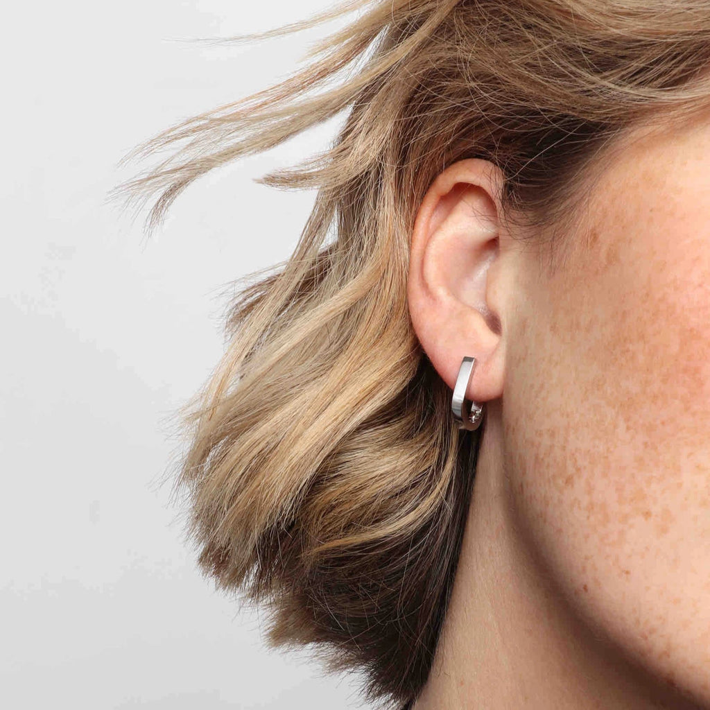 A woman wearing a pair of silver earrings.