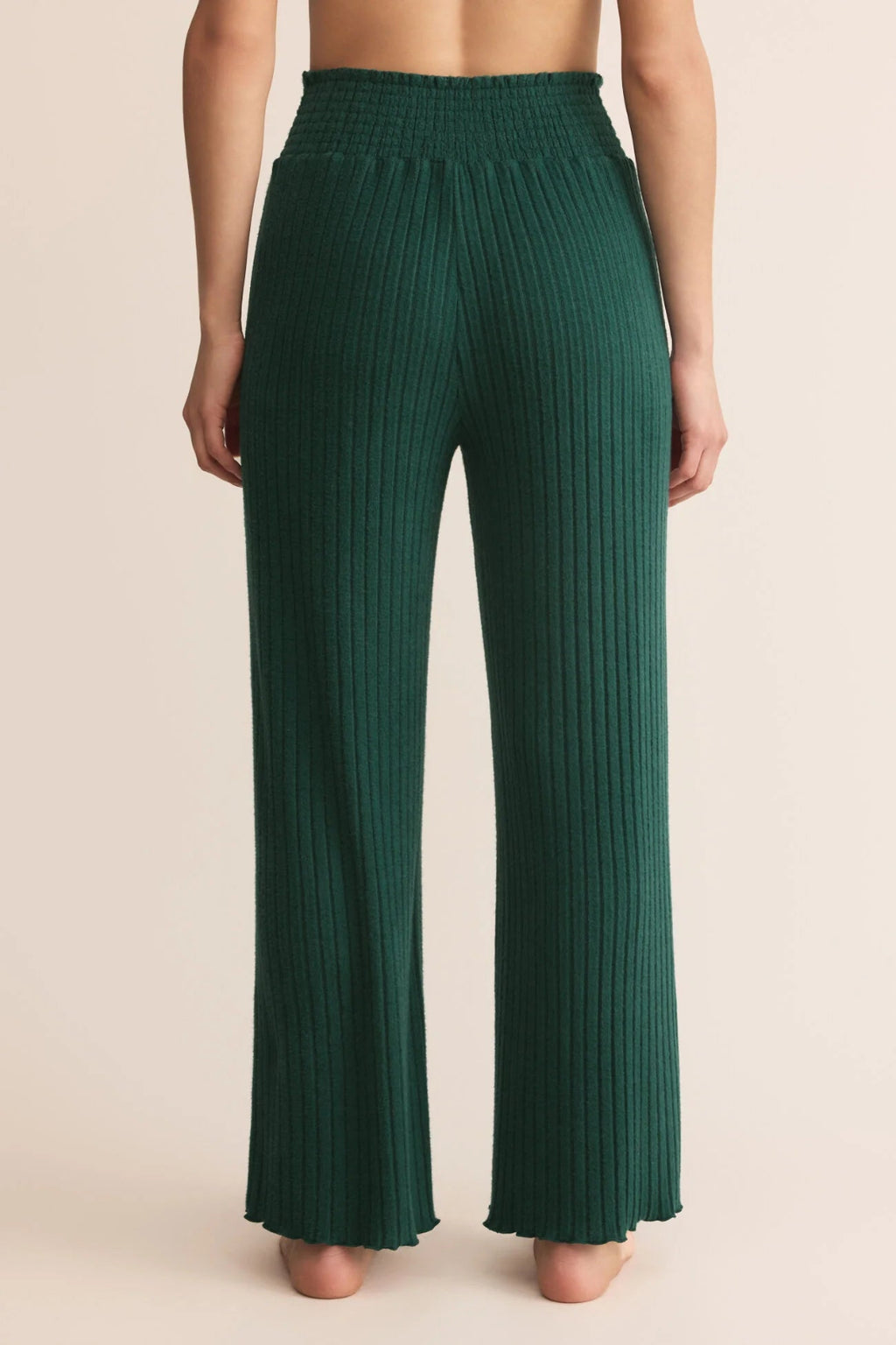Green ribbed pants worn by a person on a beige background.