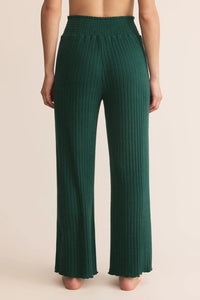 Green ribbed pants worn by a person on a beige background.