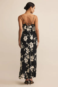 Woman wearing a black floral dress against a beige background.