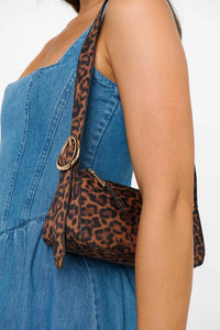 Leopard print handbag with a gold clasp held by a person wearing a blue dress.