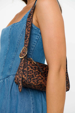 Leopard print handbag with a gold clasp held by a person wearing a blue dress.
