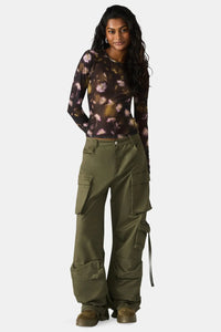 Woman wearing a tie-dye shirt and green cargo pants on a white background.