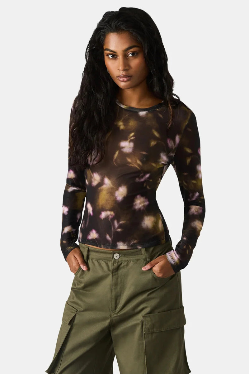 Woman wearing a long-sleeve floral top and green cargo pants on a white background.