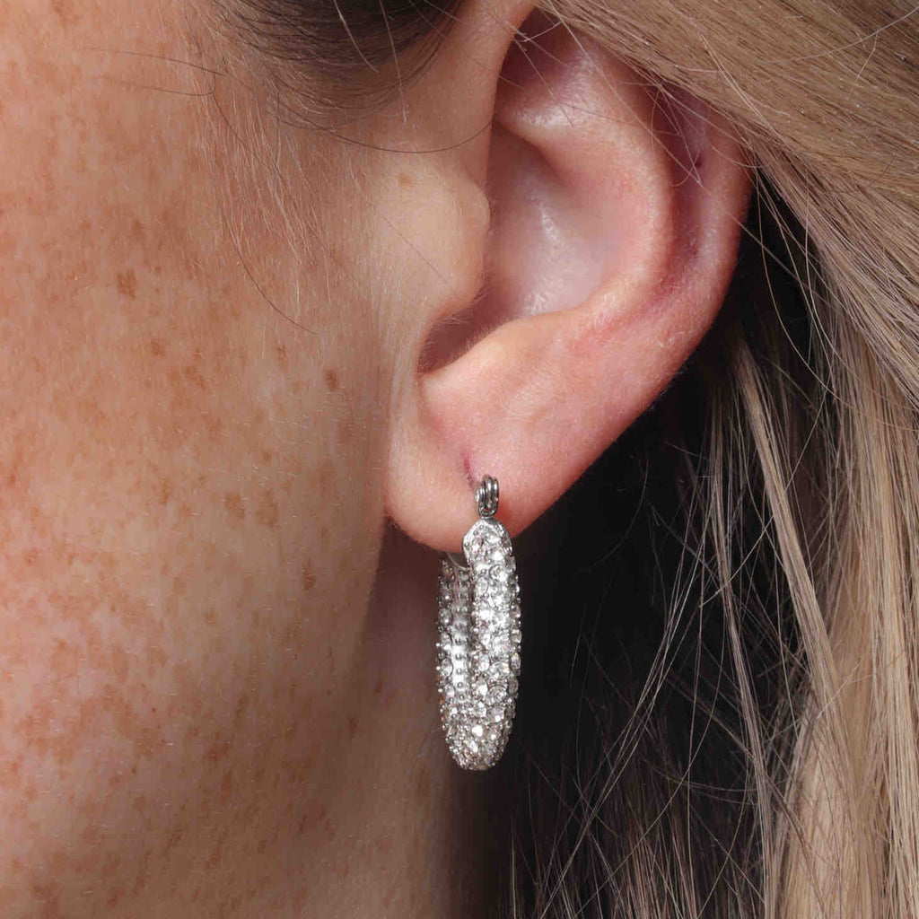 A close up of a woman wearing silver pave hoops.