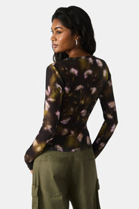 Woman wearing a long-sleeve tie-dye shirt and green cargo pants on a white background.