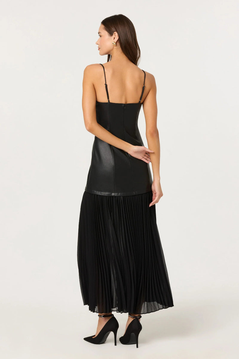 Woman wearing a black pleated dress with a sheer overlay on a white background.