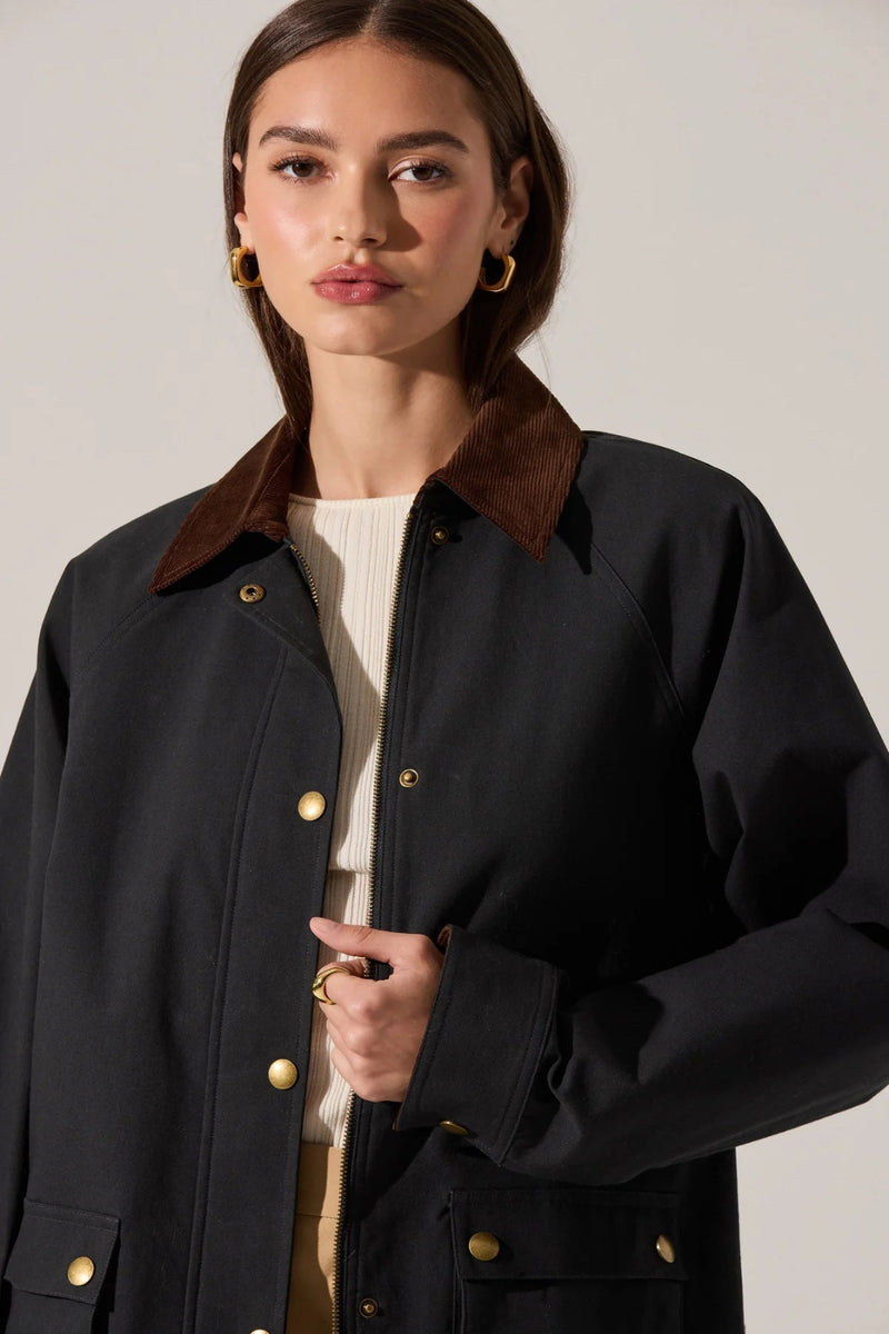 Woman wearing a dark coat with a brown collar against a plain background.