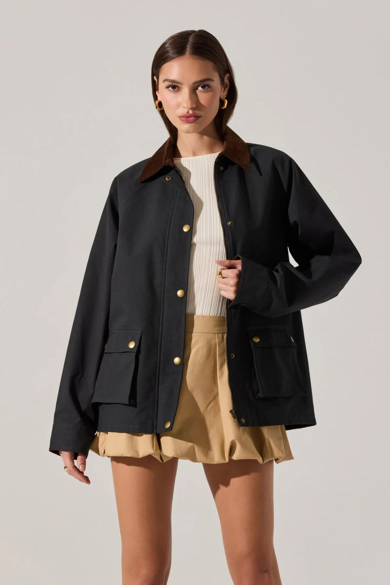 Woman wearing a navy jacket with gold buttons on a plain background.