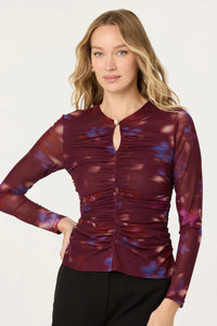 Woman wearing a burgundy long-sleeve top with a pattern on a white background.