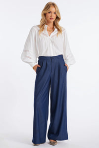 Woman wearing a white blouse and blue pants on a white background.
