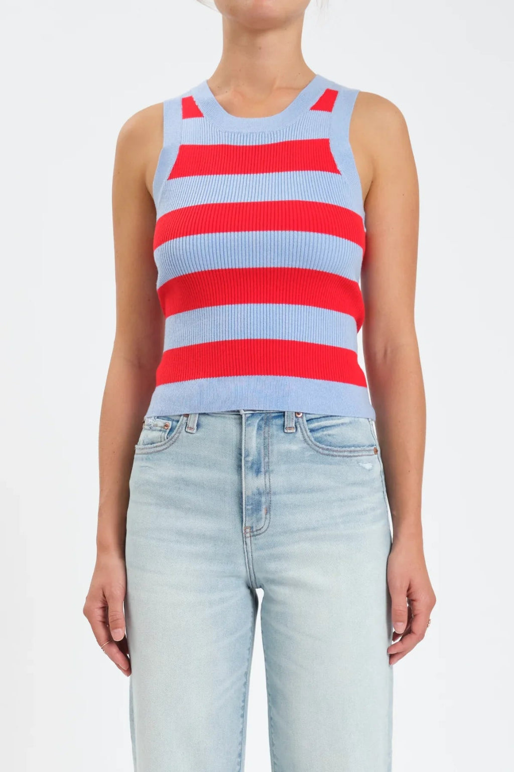 A woman wearing a red and light blue stripe tank top, with light denim jeans. 
