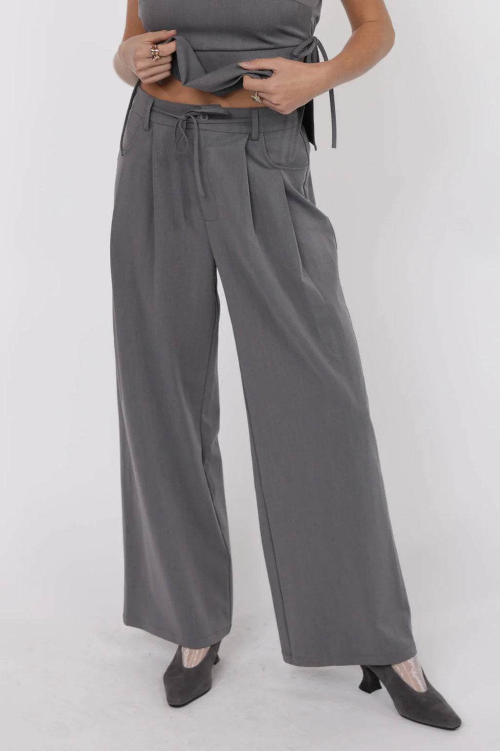 Person wearing gray high-waisted pants on a white background.