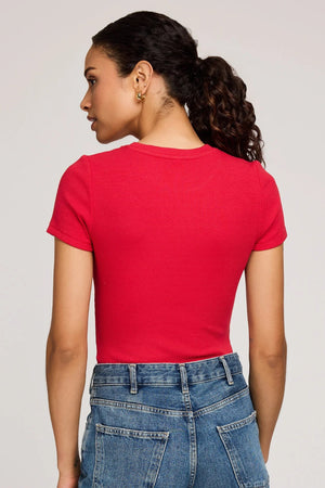 Person wearing a red t-shirt and blue jeans on a plain background.
