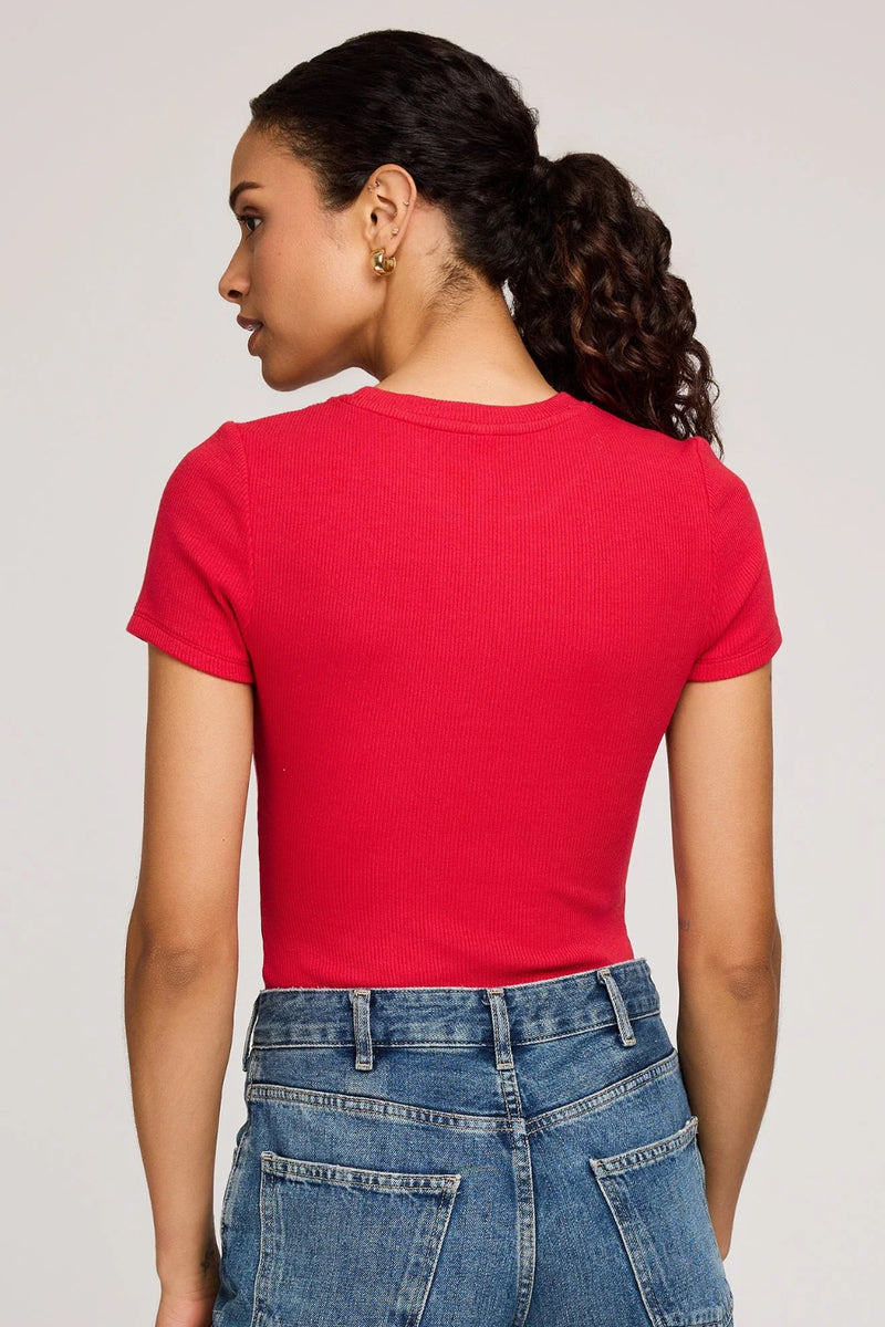 Person wearing a red t-shirt and blue jeans on a plain background.
