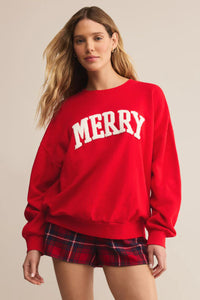 Person wearing a red 'MERRY' sweatshirt and plaid shorts on a beige background.