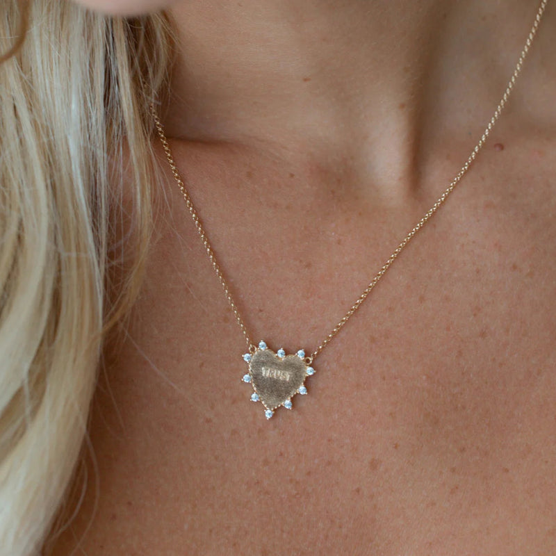 Necklace with a heart-shaped pendant worn by a person with blonde hair.